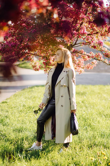 woman wearing trenchcoat under a tree with flowers