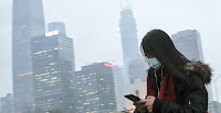 Woman wearing a mask walks to a subway in Beijing. Photo credit: Andy Wong/Associated Press