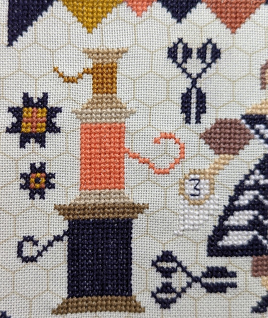 Close up of stitched thread spools, star and scissors motifs