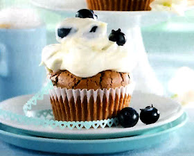 Chocolate cupcakes with a yoghurt frosting topped with blueberries.
