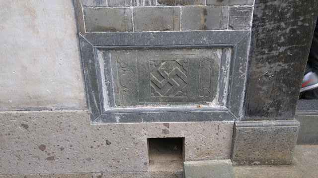 Rotated right-facing swastika in stone near a doorway.