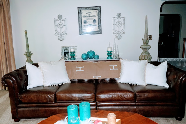 Living room with decorative iron pieces on wall, chesterfield sofa, pillows, coffee table