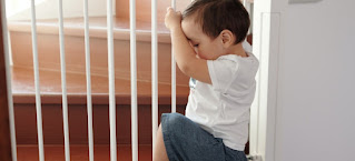 Little boy trying to climb up a stair gate.