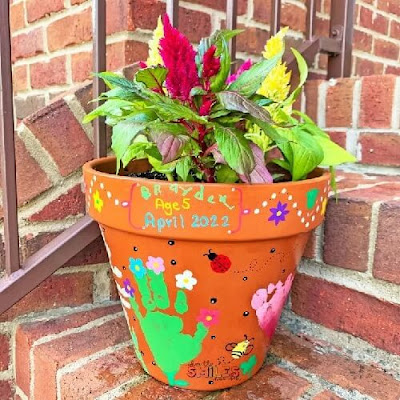 A terracotta pot with handprints and flowers painted onto it