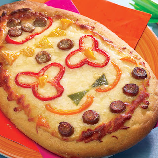 Kids Recipe Brunch Pizza--Pat the pizza dough out on a 13- by 9-inch pan, baking, sheet or a round pizza pan. Cut the ham into strips and put them on the dough. Sprinkle on the cheese.  Combine the eggs and milk in a bowl and beat to blend. Pour the eggs over the dough and sprinkle on the oregano.