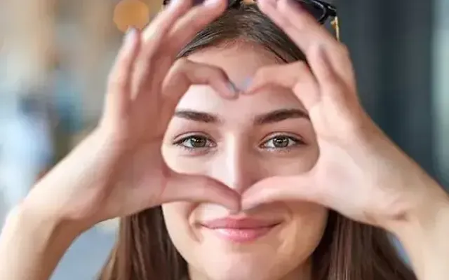 A Girl smiling and Showing a Heart Shape