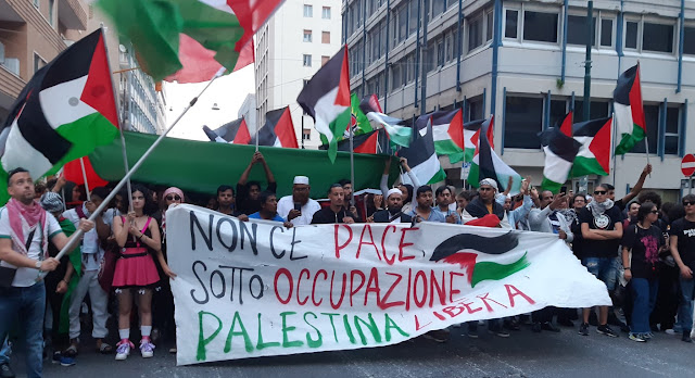 Foto di un corteo in favore della Palestina. Sullo striscione si legge: non c'è pace sotto occupazione, Palestina libera