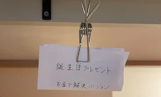 「誕生日プレゼント、お金で解決バージョン」と書かれた紙包みの写真