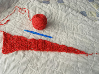 Coral yarn forms the pointy right edge of a shawl