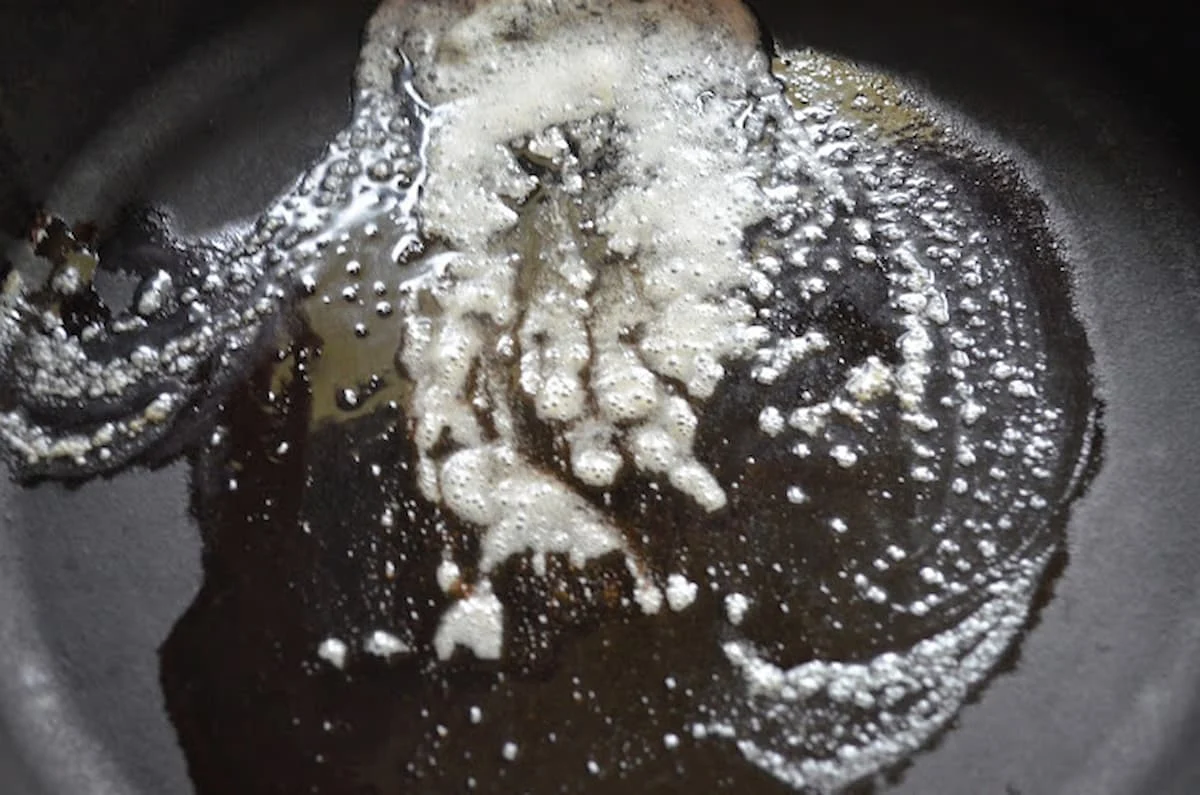 Butter melted in a black cast iron skillet.