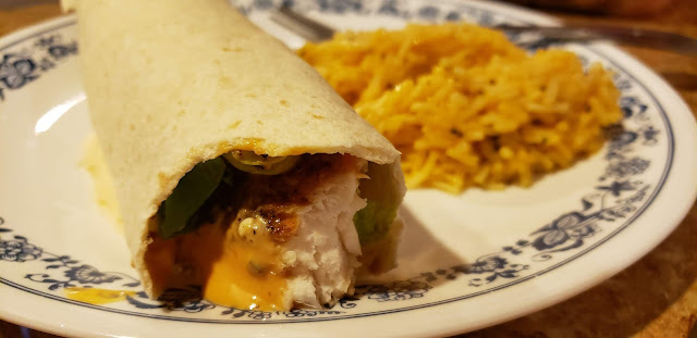 Fish taco and rice on a white plate with blue flowers.