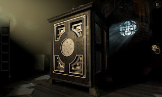 An intricate wood and brass puzzle box on a table in the attic in front of a round window