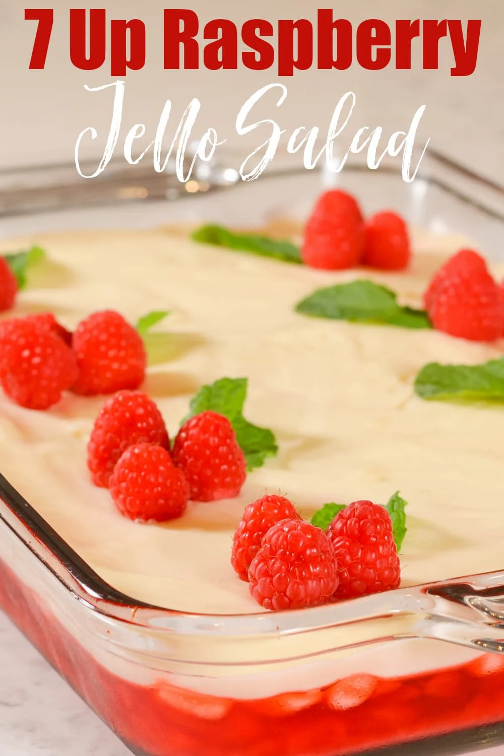 A side shot of a glass pan full of 7 Up Raspberry Jello with red text on top 7 Up Raspberry and directly below white text Jello Salad.