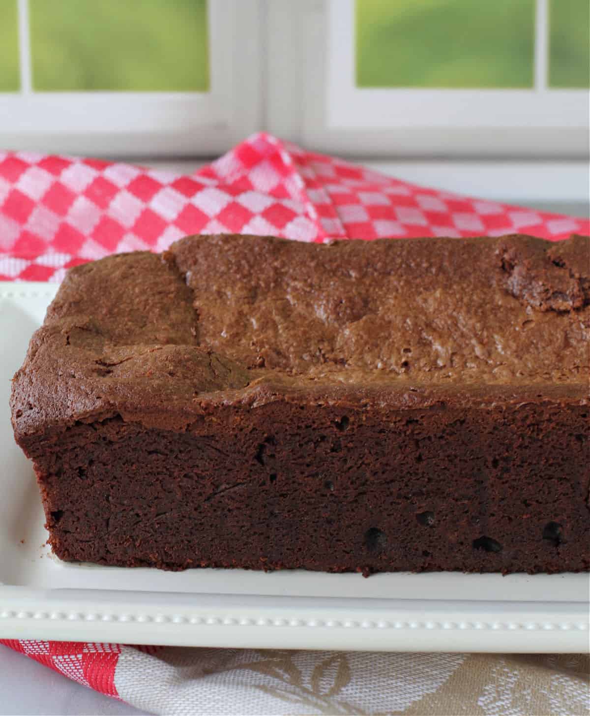 Half-baked chocolate cake loaf on a white platter.