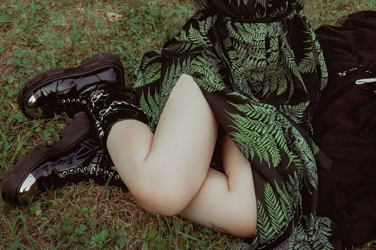 woman in altr fashion look and platform boots is posing on a grass