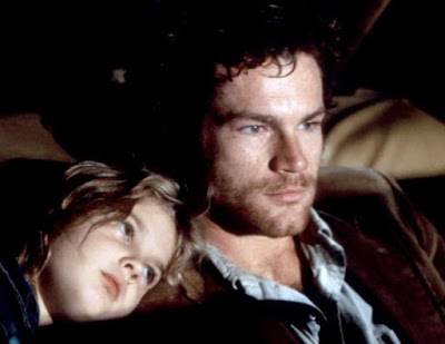 Drew Barrymore leans on David Keith's shoulder while they are on the run in a movie scene from 1984's horror film Firestarter