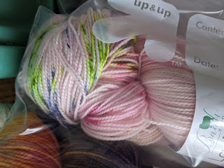 The end of a skein of sock yarn. It's a pale pink with pops of purple, green, blue and others.