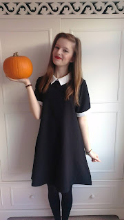 Me wearing my Wednesday Adam's style dress, a picture for my first ever lookbook, holding pumpkin in right hand and smiling merrily to the camera with red lips.