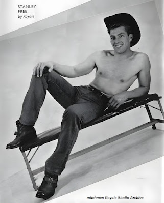 Bare top muscular model reclining on bench in jeans, cowboy hat + studded belt