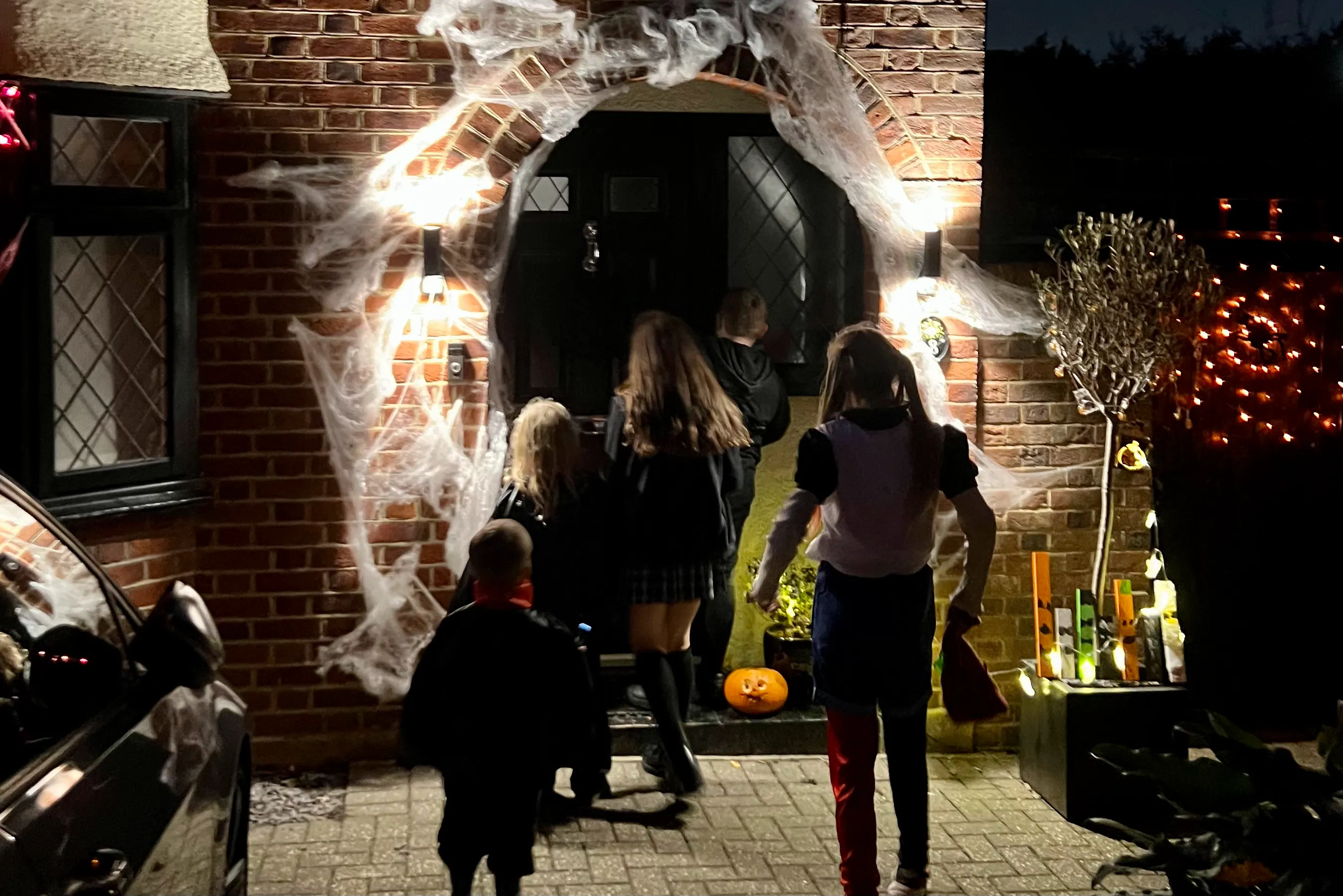 A group of children going up to a Halloween decorated door to trick or treat