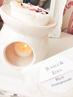 Bumble and Eden Black Pomegranate wax melt, melting in wax melter with small white tea light below and packet held adjacent.