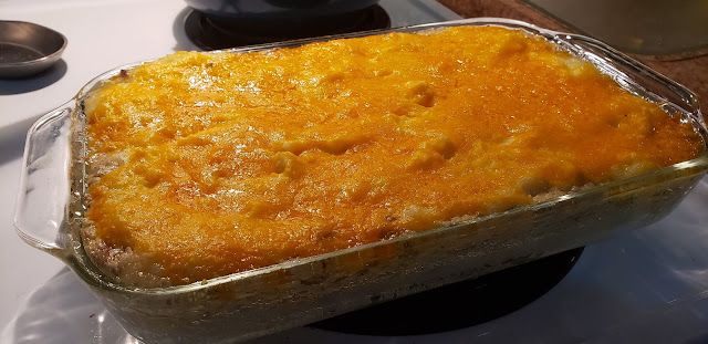 Glass Casserole dish of Miss Maggie's Potatoes covered with melted shredded cheese.