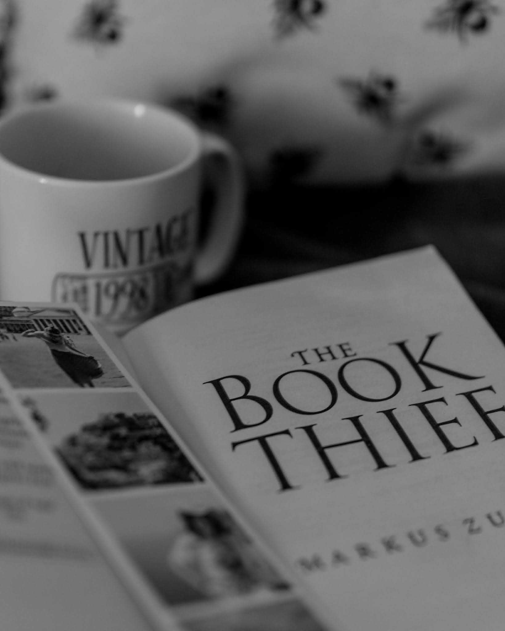 black and white image of open book the book thief by markus zusak with bookmark photostrip and white mug