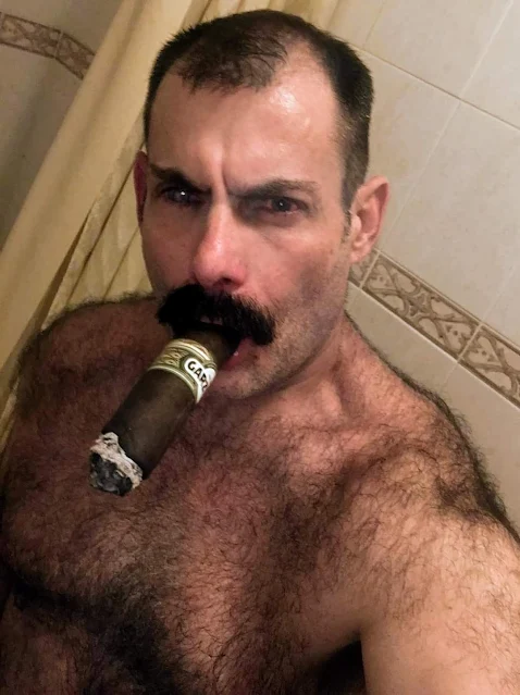 Hairy chested shirtless handsome man with a cigar in his mouth and a glass eye