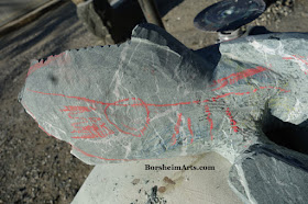 Carving notes marked with red chalk on green marble carving in progress