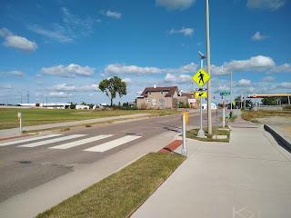 wide sidewalk, perpendicular to crosswalk with signal