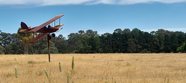 Low flying plane (on a pole) in the front field.