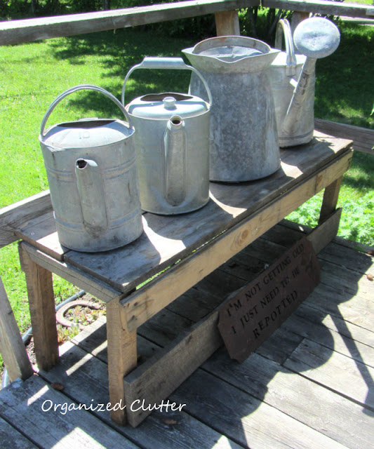 Rustic Bench with Vintage Watering Cans www.organizedclutterqueen.blogspot.com