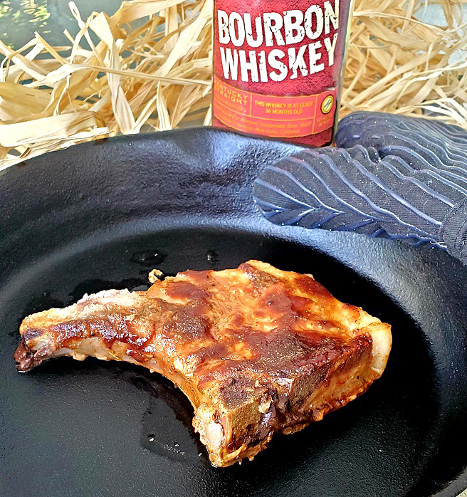 this is a cast iron skillet of pork chops with a bourbon barbecued glaze on top