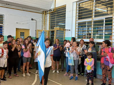 Foto 4: Alumna ingresando con la bandera argentina de ceremonia y toda la comunidad educativa aplaudiendo.