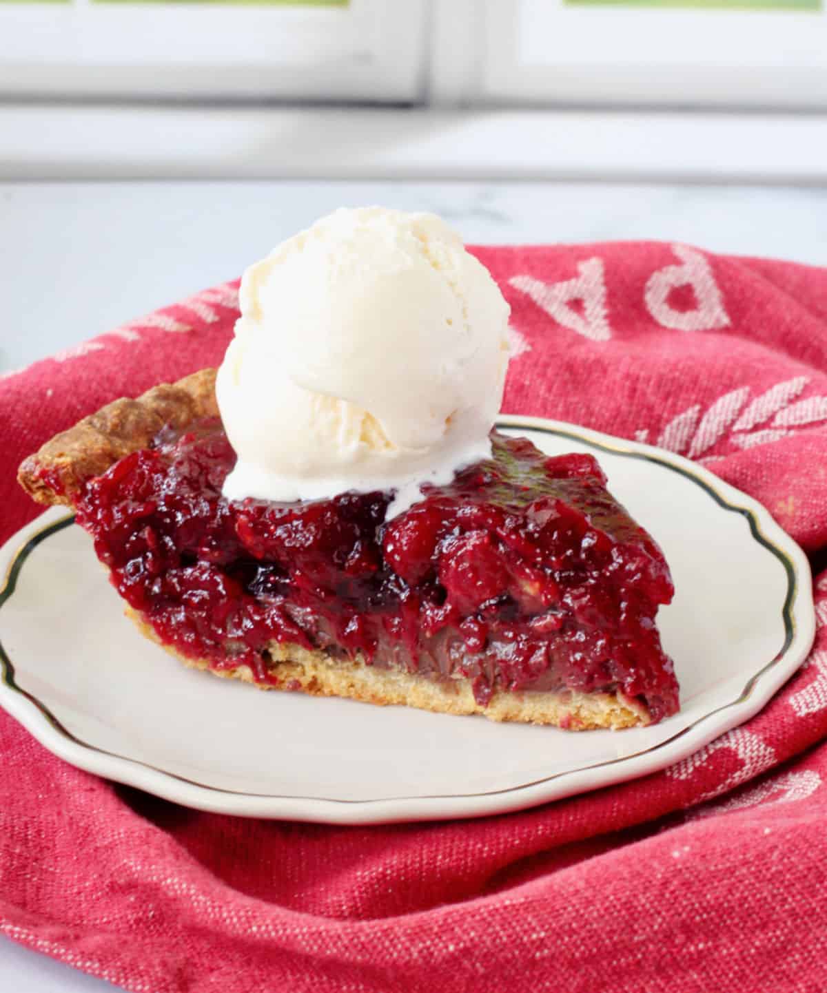 Slice of Cranberry and Fudge Layered Pie with vanilla ice cream on top.