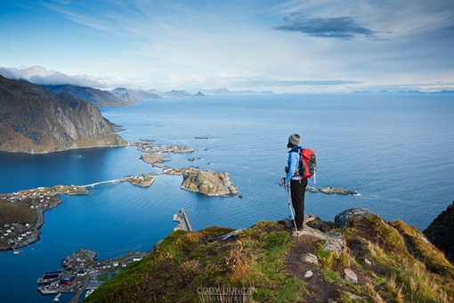 Female hiker enjoys spectacular view over mountains and fjords from Reinebringen, Lofoten islands, Norway