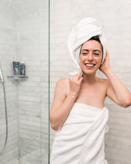 A woman smiling in the mirror wrapped in a towel