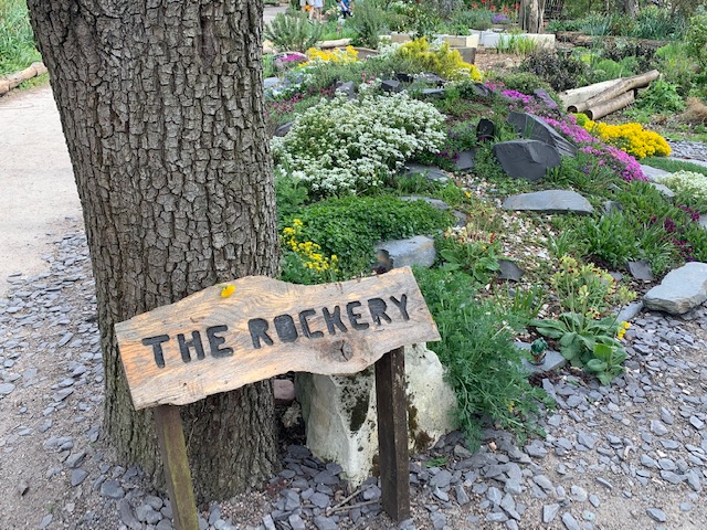 Wooden sign for The Rockery in a peaceful garden