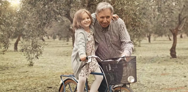 Un abuelo y su nieta disfrutando de un paseo en bici a través de los olivos