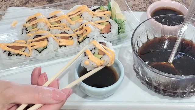 Sushi being dipped  in a sauce.