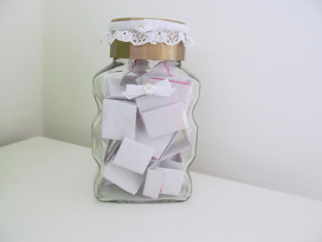 old coffee jar with lace attached to lid filled with folded bits of paper