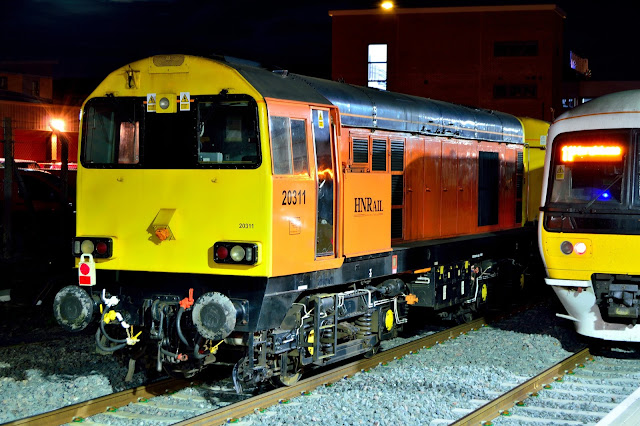 night photo of HN Rail class 20311 diesel locomotive in orange livery waits at Banbury station, England, 2017