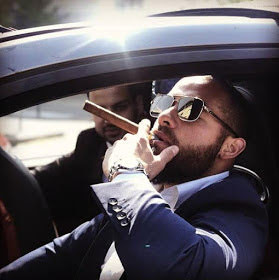Sexy man smoking a cigar in car with shades on.