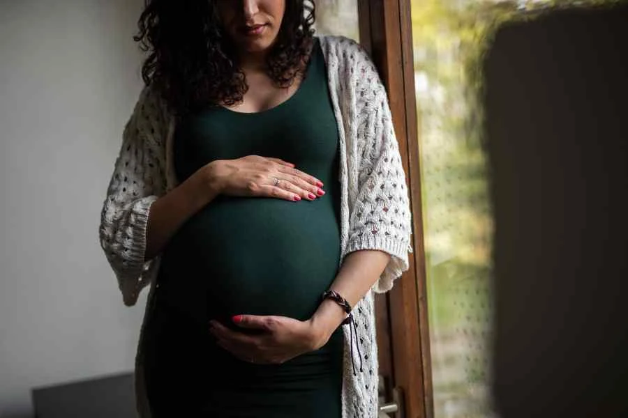 A woman looking chic and comfortable while holding here pregnant belly