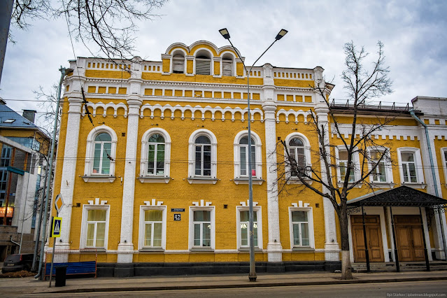 Трехэтажное желтое здание с декором из белого кирпича