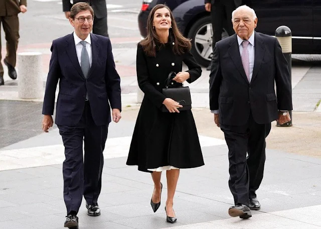 Queen Letizia wore a black v-neck silk shirt by Sandro. Carolina Herrera double-breasted wool coat. Adolfo Dominguez skirt