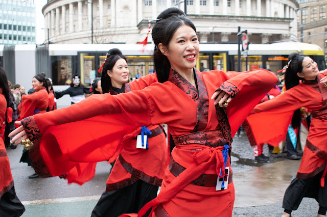 Dancer dressed in traditional red costume in front of Manchester Central Library