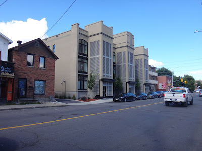 Beige development with large bay windows and enclosed front stairs, double-width driveway has a dropped sidewalk. (509-511-515 Gladstone, north side, west of Lyon Street)