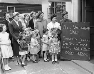 Um grupo de mães com seus filhos espera do lado de fora da Clínica do Conselho do Condado de Middlesex pela primeira vacinação contra a poliomielite em maio de 1956.