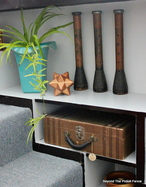 Vintage textile bobbins on a painted bookshelf